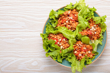 Lettuce wraps filled with a savory mixture of minced meat, herbs, and spices, creating a flavorful and refreshing appetizer or light healthy meal high in protein, copy space