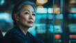 © LucyJ - An East Asian older professional woman, smartly dressed in a modern business environment, successful in her career, wide landscape format 16:9 with copy space, blue grey tones, advertising style photo