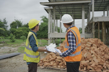 Professional architect engineer with hard hat and blueprint at building construction site house building permit background. Architects looking at blueprints. Construction and engineering industry