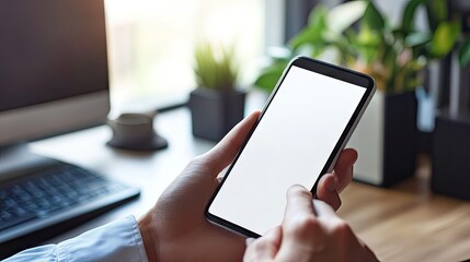 Poster - Close-up of a man hand texting on a blank white screen cell phone at a home office desk.
