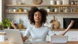 © Hailie - Woman meditating with two laptops in bright kitchen