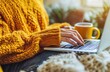 © Cetin - woman in yellow sweater typing on laptop with coffee cup beside her at wooden table