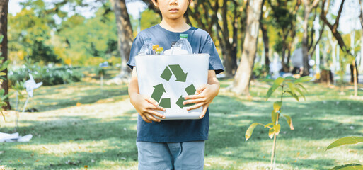 Wall Mural - Cheerful young asian boy holding recycle symbol bin on daylight natural green park promoting waste recycle, reduce, and reuse encouragement for eco sustainable awareness for future generation. Gyre