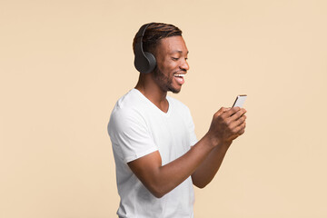 Aufkleber - Cheerful Black Guy Wireless Headphones Using Mobile Phone Standing Over Yellow Background. Studio Shot