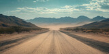 A long desert road with mountains in the background, dusty and sandy