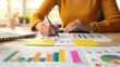 © KKC Studio - Diligent Financial Analyst Reviewing Reports with Cluttered Desk of Charts and Graphs - Financial Analysis Concept