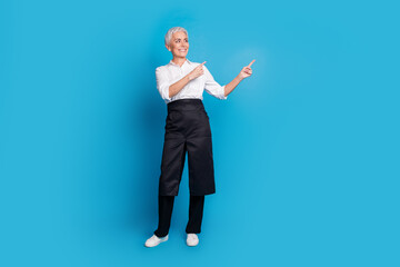 Canvas Print - Full size photo of retired female barista coffee shop owner point look empty space wear waitress uniform isolated on blue color background