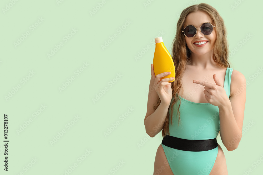 Beautiful young woman with sunscreen cream on green background
