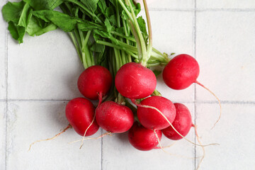 Wall Mural - Fresh radishes with leaves on light tile background