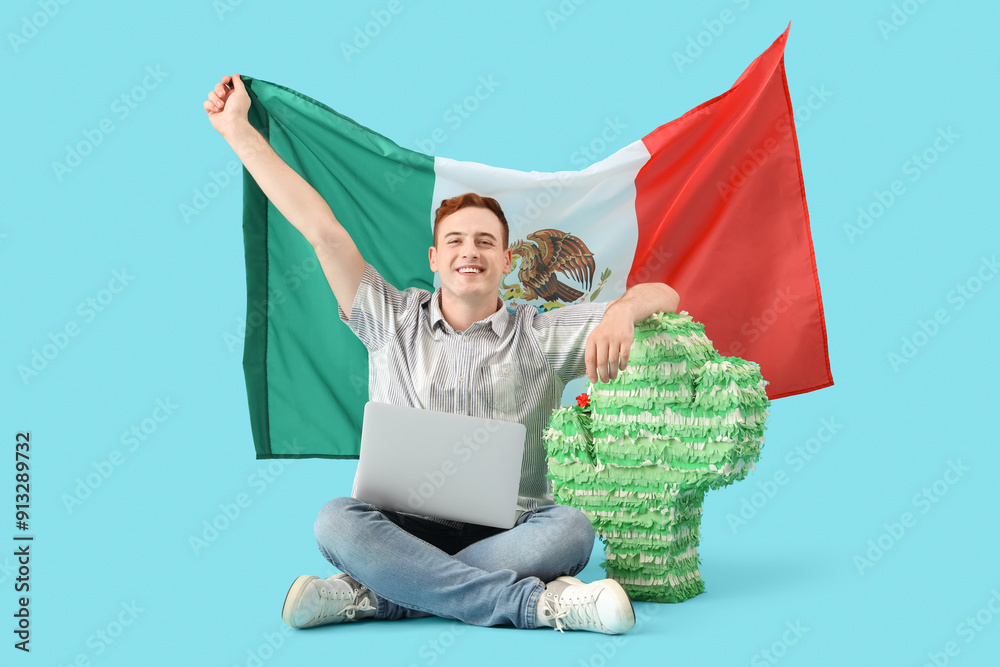Young man with Mexican flag and pinata sitting on blue background
