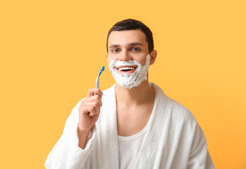 Sticker - Handsome young man with razor and shaving foam on his face against yellow background