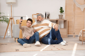 Wall Mural - Happy grandfather with his cute grandson taking selfie at home