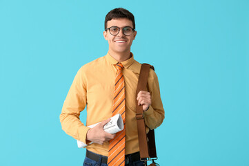 Wall Mural - Smiling young man with striped tie and newspaper on blue background