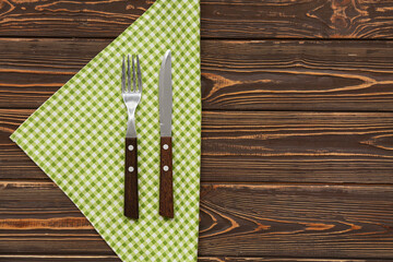 Wall Mural - Checkered napkin and cutlery on wooden background