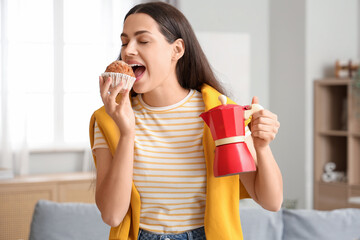 Wall Mural - Pretty young woman with geyser coffee maker and muffin at home