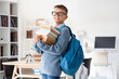 © Pixel-Shot - Teenage boy with backpack and stack of books in library