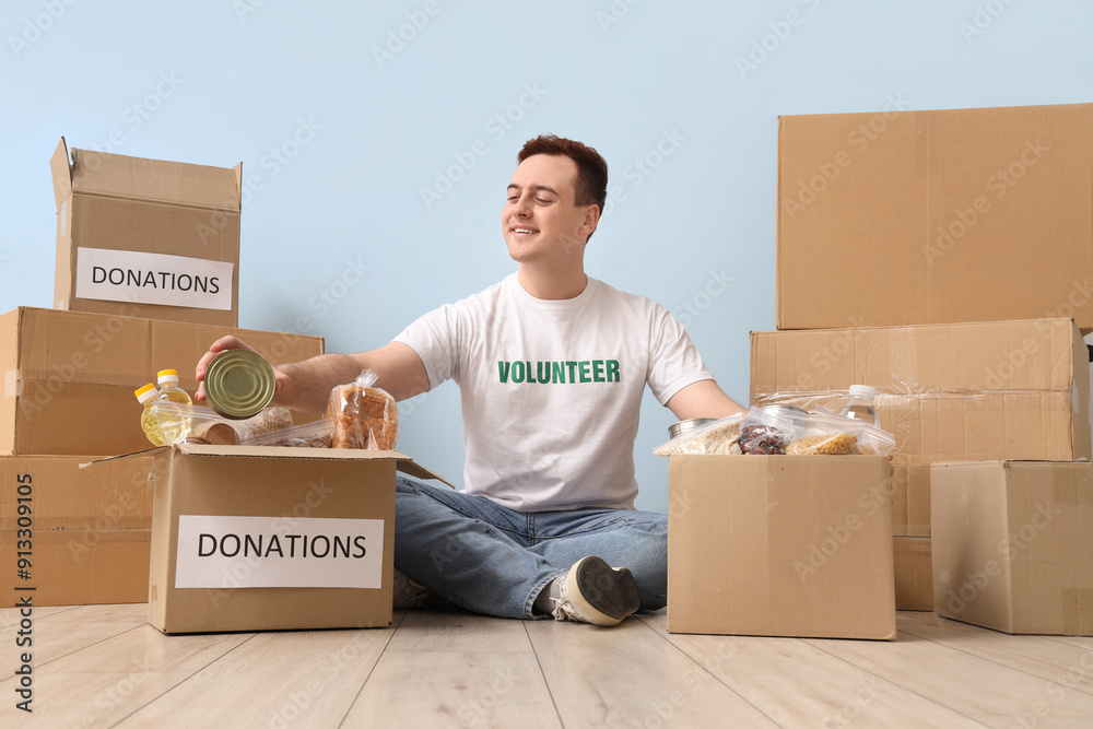 Male volunteer with donation boxes near blue wall