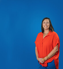 Headshot of Caucasian brunette middle age business woman in studio on blue backdrop with copy space