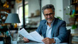 © Nataly - Portrait of a smiling businessman in his office. Adult man reading business papers and smiling.