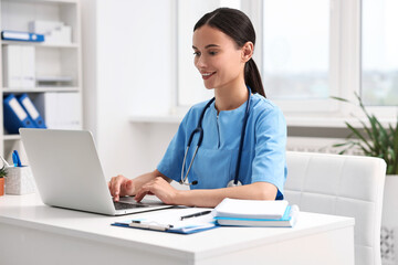 Poster - Smiling nurse working with laptop at table in clinic