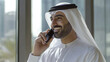 © Hound - An Emirati man in his mid thirties, wearing a white long sleeve kandura with black and grey keffiyeh is talking on the phone inside an office building