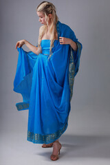 Wall Mural - Pretty blonde woman in blue Indian sari on grey background