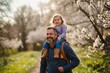 © LIFE LINE - Dad having fun with young daughter, carry her on shoulders, walking in spring nature