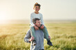 © StarDweller/peopleimages.com - Piggyback, father and portrait of son in nature, love and smile for family in space, sunshine and grass. Countryside, dad and visit of Texas with boy for fresh air, man and bonding with child in farm