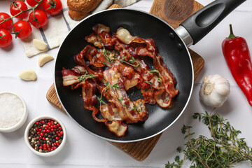 Wall Mural - Delicious bacon slices in frying pan and products on white tiled table, flat lay