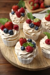 Wall Mural - Tasty cupcakes with different berries and mint on wooden table, closeup