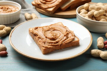 Poster - Tasty sandwich with peanut butter and nuts on light blue wooden table, closeup