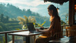 © Nittaya - Young female freelancer sitting in terrace cafe, Working online and enjoying mountains view