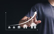 © Pakin - Real estate market growth and home investment concept. Real estate economic growth analysis. Person touching the real estate growth graph on virtual screen.