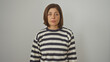 © Krakenimages.com - A middle-aged hispanic woman in a striped sweater poses against a white wall, looking neutral.