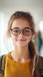 © Naphol - A cheerful young girl with glasses smiles warmly, showcasing her bright personality and the joy of learning in a modern environment.