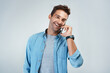 © Chanelle2000/peopleimages.com - Phone call, smile and thinking with man in studio on white background for communication or conversation. Contact, funny and laughing with happy person speaking on mobile for chatting or networking