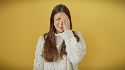 Canvas Print - A young hispanic woman in a white sweater poses with a smile, touching her head against an isolated yellow background.