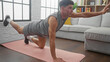 © Krakenimages.com - Young man doing one-arm pushups in a modern living room, showcasing fitness and determination indoors.