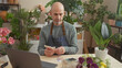 © Krakenimages.com - A bald man counting icelandic krona at a flower shop filled with various plants and flowers indoors.