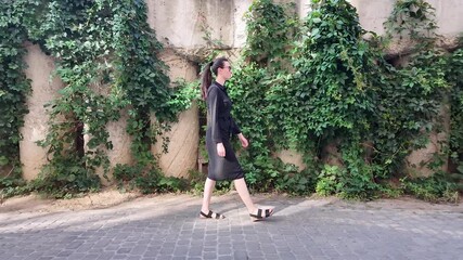 Poster - Woman walking in the city wearing elegant black dress