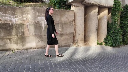 Canvas Print - Woman walking in the city wearing elegant black dress