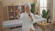 © Krakenimages.com - Woman enjoying spa session taking selfie holding wineglass in wellness center with massage table and beauty products