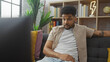 © Krakenimages.com - Handsome black man sitting on a couch in his living room, watching tv with a thoughtful expression.