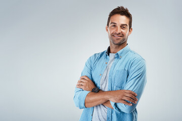 Poster - Portrait, space and happy man with arms crossed, fashion or trendy outfit for confidence on grey background. Model, mockup or creative male designer with proud smile, modern clothes or style to relax