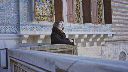 Wall Mural - A smiling woman enjoys the architecture at istanbul's historic topkapi palace, showcasing tourism and culture.