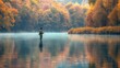 © vadosloginov - A lone fisherman stands in the middle of a lake on a foggy autumn day, casting his line into the still water. Colorful fall leaves adorn the trees lining the banks of the lake. The reflection of the t