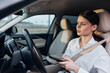 © SHOTPRIME STUDIO - Woman in car, drivers seat, holding phone, looking at screen a woman sits in the driver seat of a car, holding and looking at her cell phone, illustrating the concept of distracted driving