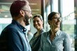 © Victor Bertrand - Three colleagues smiling and conversing, captured in a candid moment in a bright, modern office space.