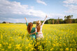 © maxbelchenko - Two young women in a beautiful field with yellow flowers. Summer day walks in flower plantings. Girlfriends together.