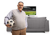 © Ljupco Smokovski - Elderly man holding a football in front of tv and smiling